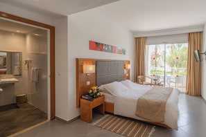 Une chambre d’hôtel avec un lit, une table de chevet avec une lampe, un miroir, une douche et une vue sur l’extérieur.