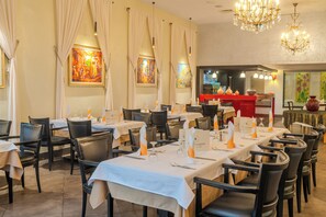 Un restaurante con varias mesas dispuestas para comer, con una zona de bar al fondo.