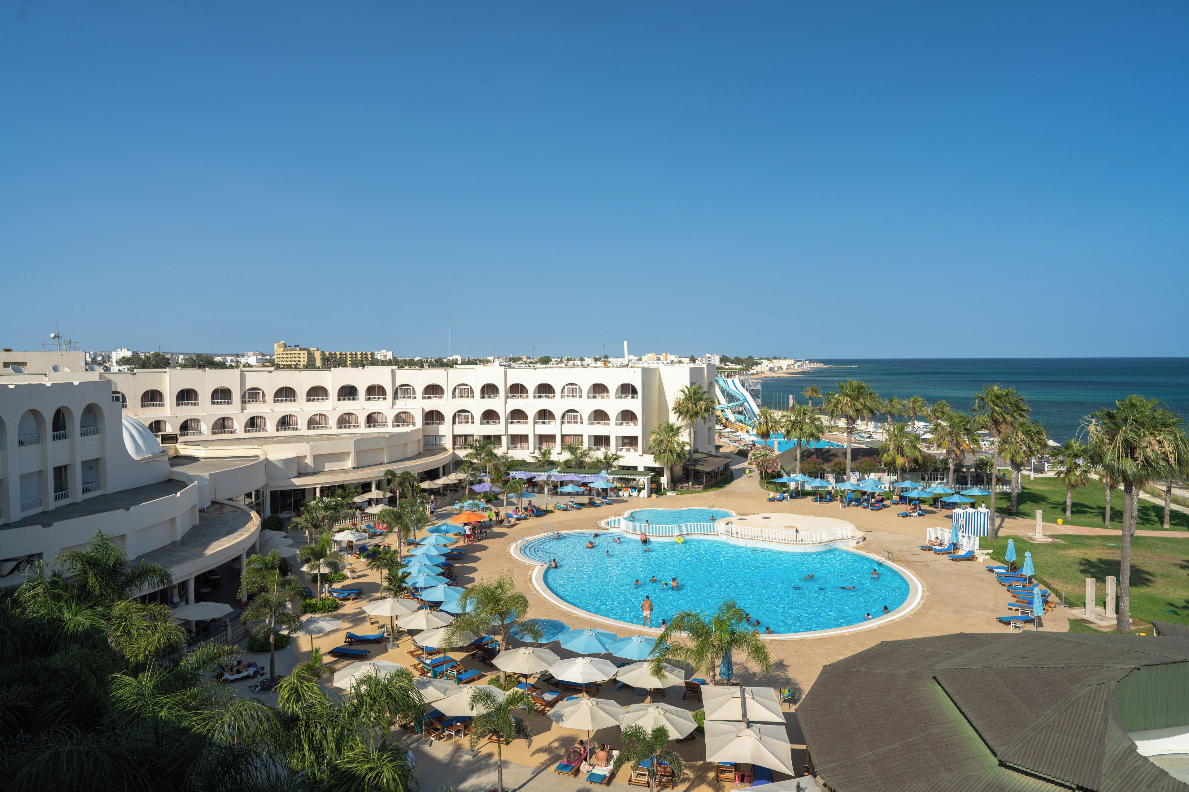 A resort with a large pool, multiple swimming areas, and a beach.