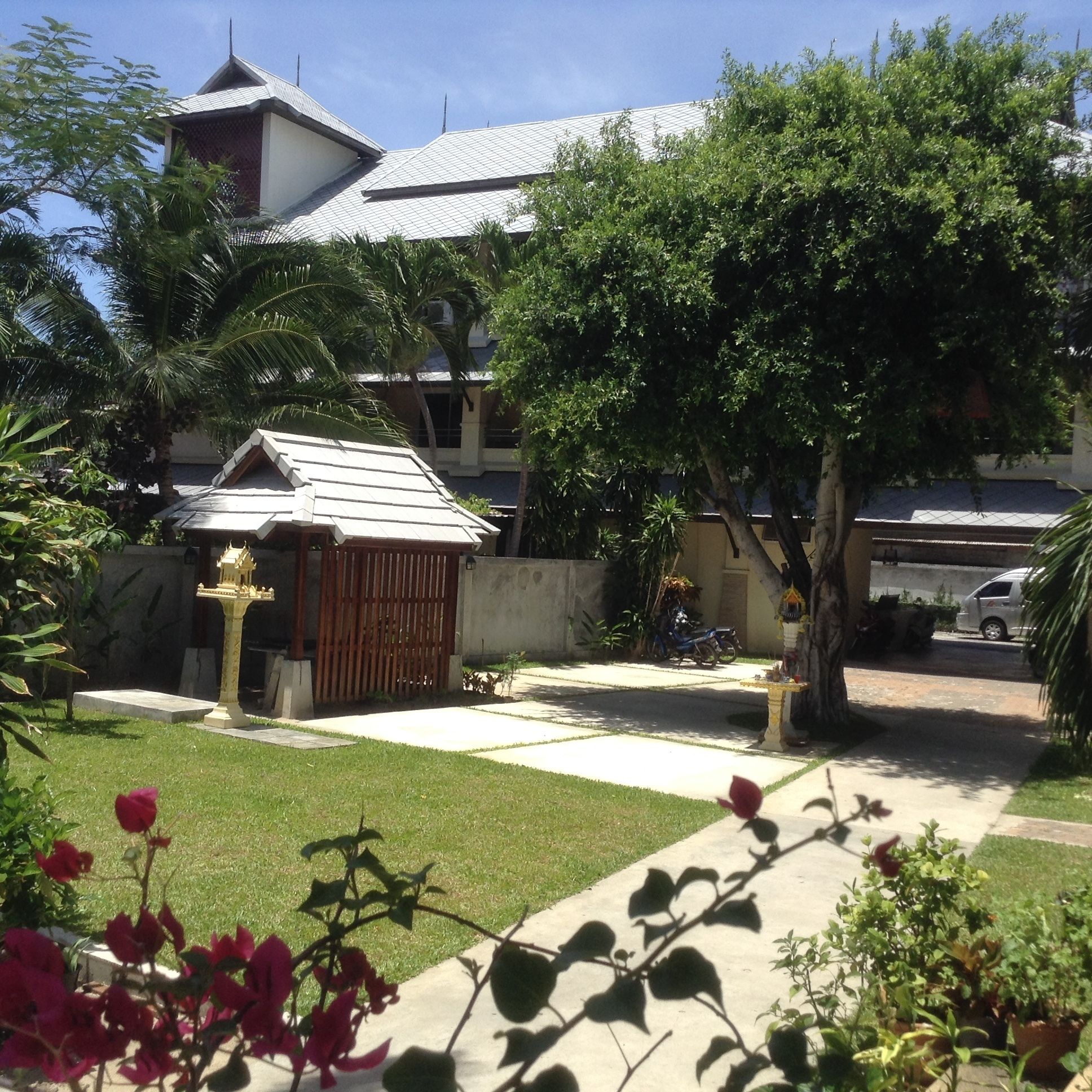 A residential area with a house, a small shrine, and a tree.