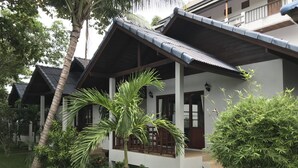 A bungalow with a covered porch, surrounded by lush greenery and palm trees. - Marina Beach Resort (Koh Samui)