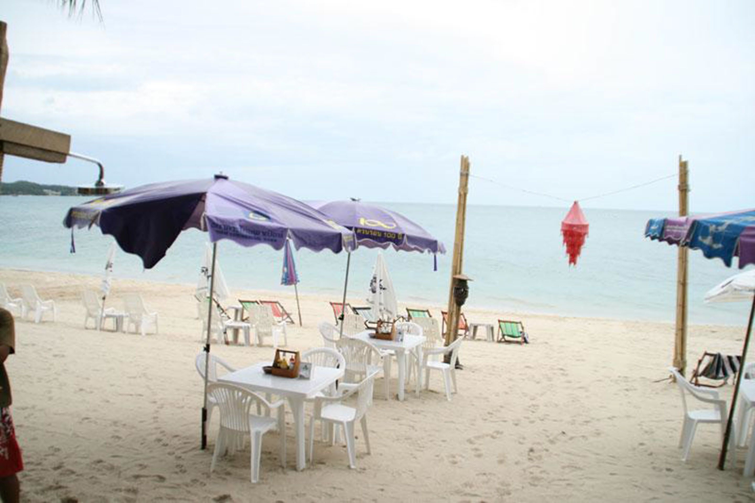 A beachside restaurant with outdoor seating and umbrellas.