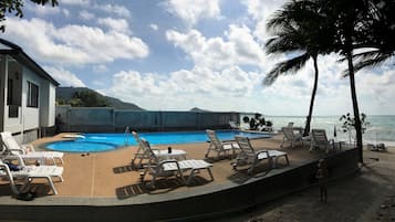Una piscina al aire libre, sillones reclinables de piscina