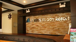 A reception desk at Marina Beach Resort with a stone wall backdrop and a clock on the wall. - Marina Beach Resort (Koh Samui)