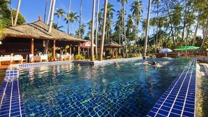 A swimming pool with tiled edges, surrounded by palm trees and a thatched-roof structure. - Lipa Bay Resort (Koh Samui)