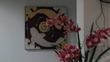A room with a wall-mounted artwork featuring a stylized design and a potted orchid plant.