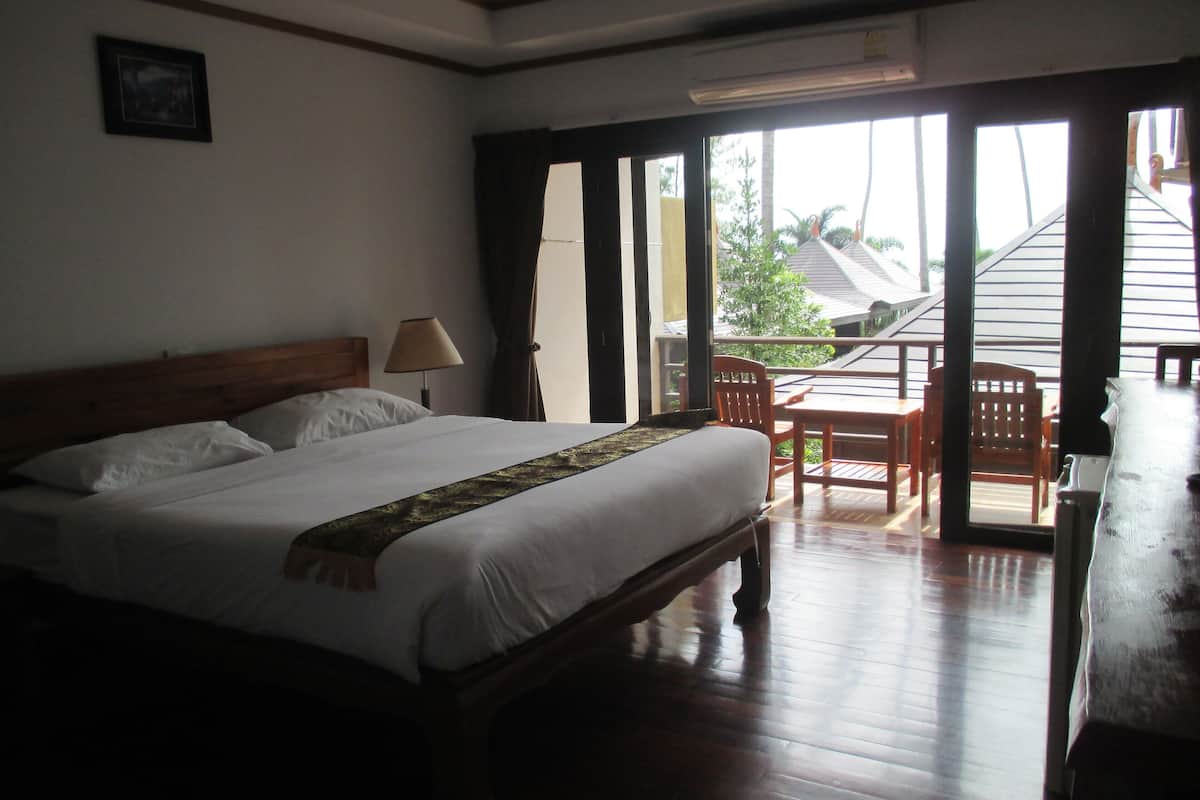 A hotel room with a bed, a desk, a chair, and a view of the outside.