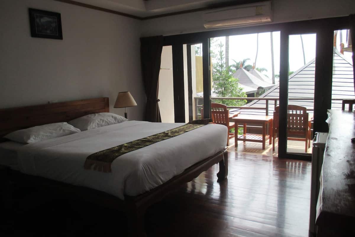 A hotel room with a bed, a desk, a chair, and a view of the outside.