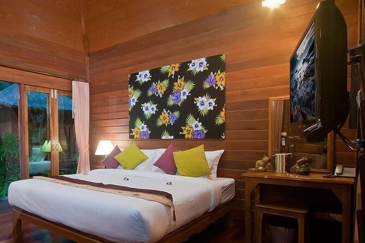 A wooden room with a bed, a desk, and a television.