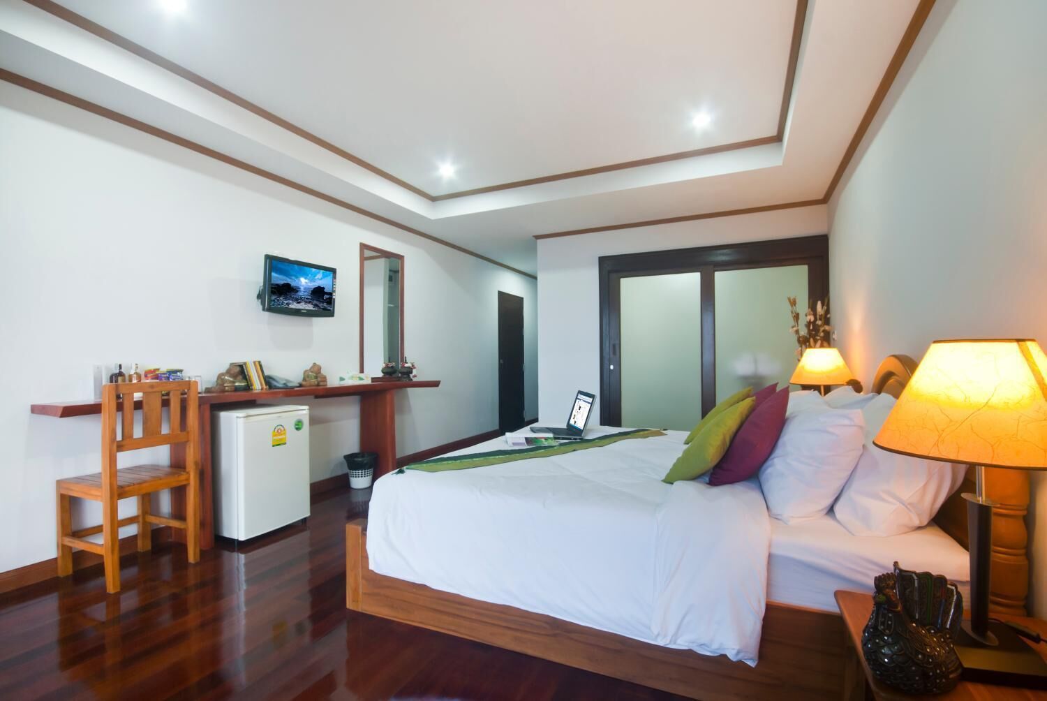 Ein Hotelzimmer mit Bett, Schreibtisch, Stuhl und Fernseher an der Wand.