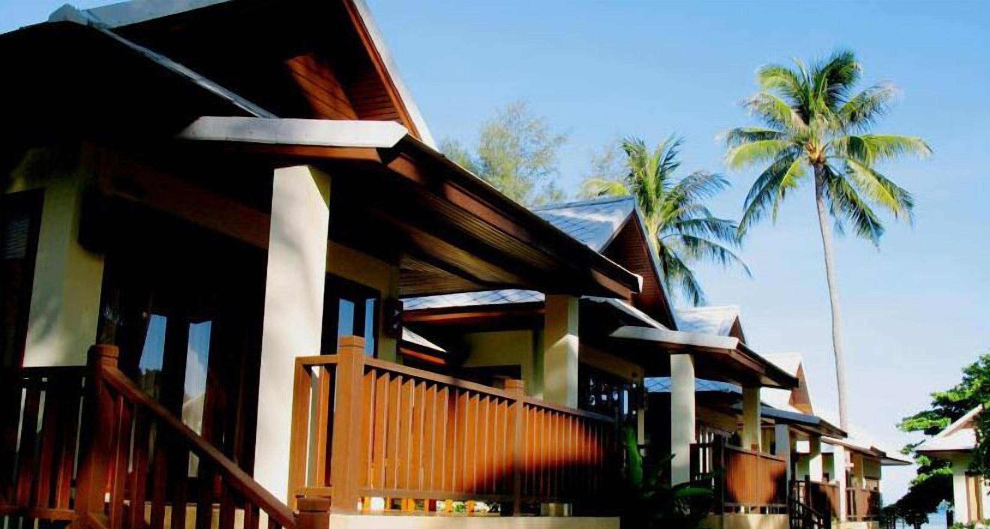 A resort with wooden balconies and palm trees in the background.