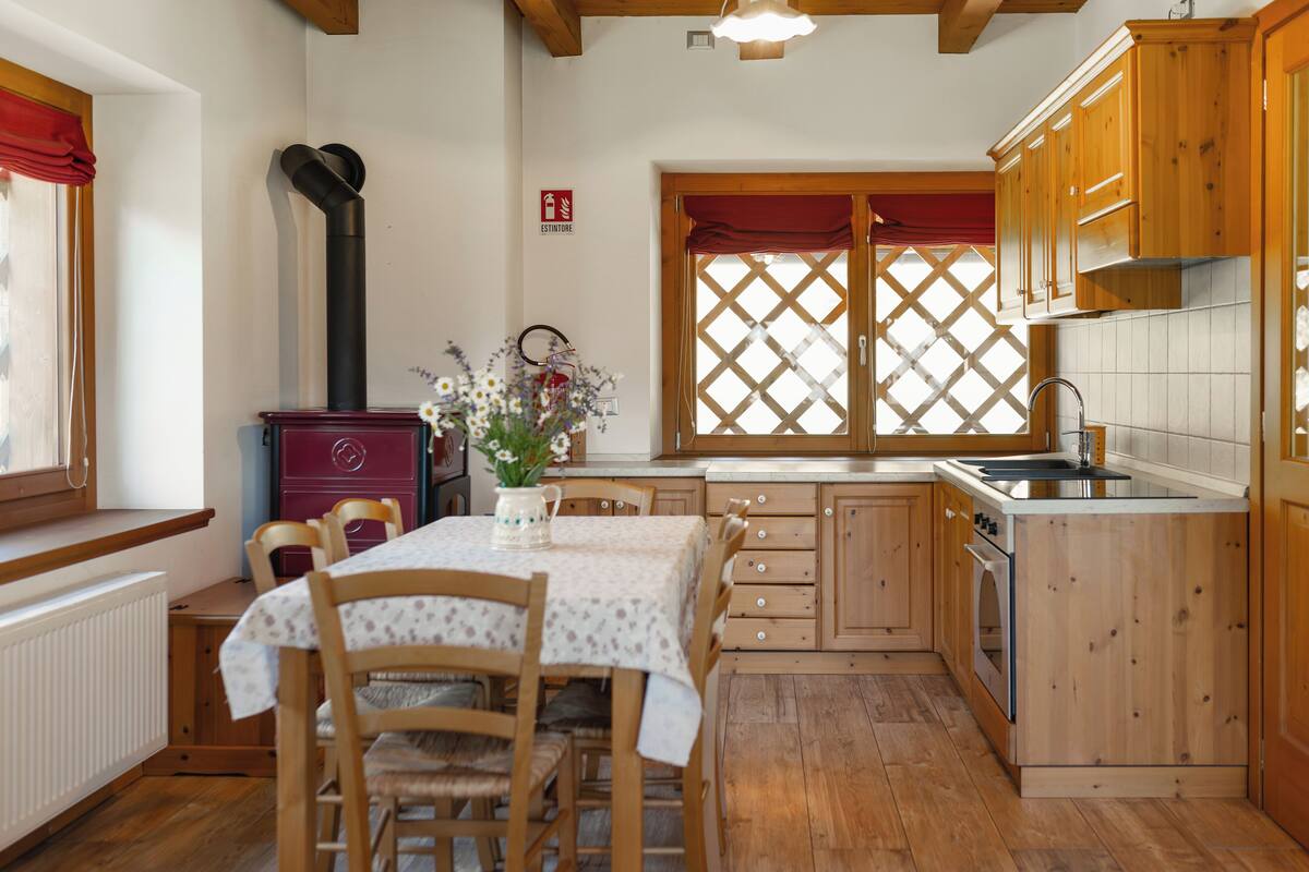 A kitchen with wooden cabinets, a stove, and a dining table with chairs.