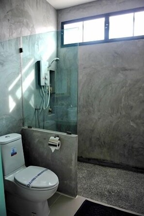 Un baño con inodoro, cabina de ducha de vidrio y pared de mármol.