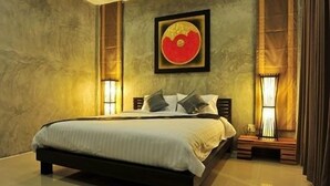 A bedroom with a large bed, a framed artwork above the bed, and two bedside lamps. - The Gleam Resort (Satun)