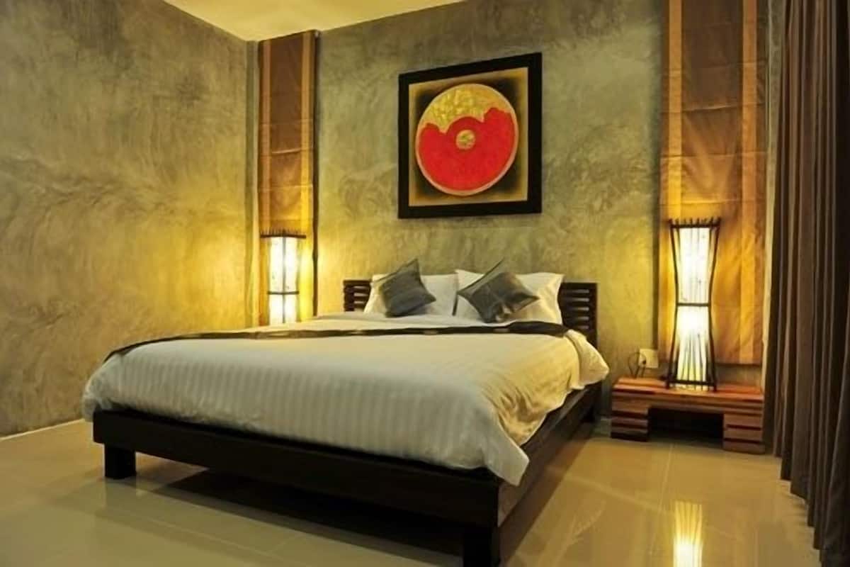 A bedroom with a large bed, a framed artwork above the bed, and two bedside lamps.