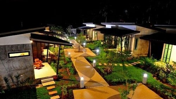 A modern resort with a central pathway leading to multiple villas, surrounded by lush greenery and well-lit pathways. - The Gleam Resort (Satun)