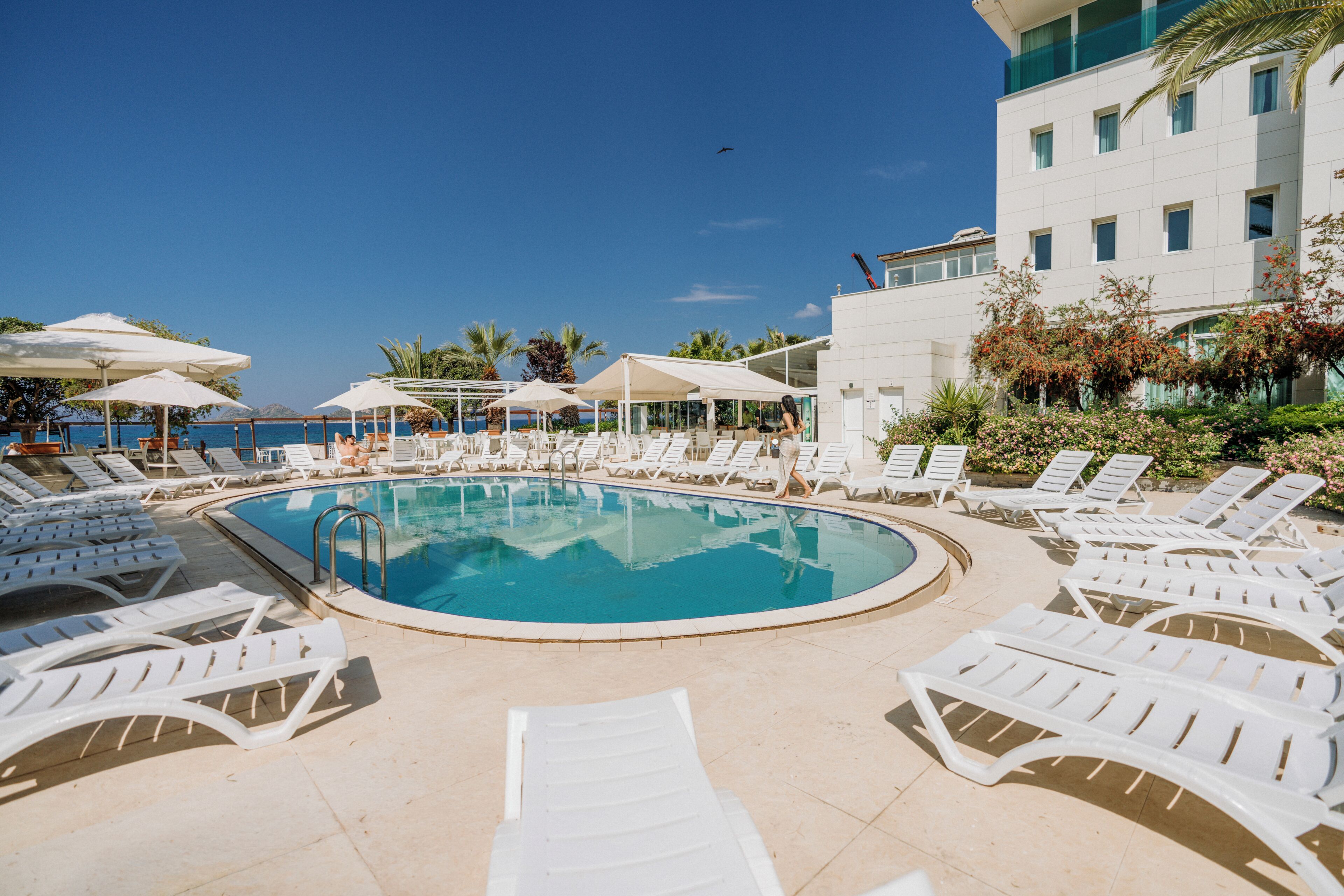 Una piscina al aire libre, sombrillas, sillones reclinables de piscina
