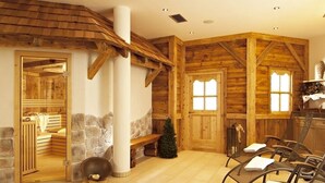 Un intérieur rustique en bois, avec un sauna, des murs en pierre et un coin salon équipé de serviettes.