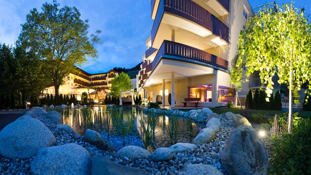 Un hôtel doté d’une piscine entourée de rochers et d’arbres, et offrant plusieurs balcons ainsi que des espaces de détente en plein air.