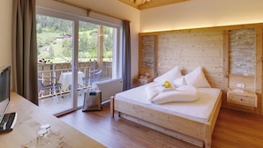 Une chambre à coucher avec un plafond en bois, un grand lit, un bureau avec un ordinateur portable et une vue sur un jardin, accessible par une porte coulissante.