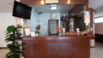 Un mostrador de recepción con un televisor, diplomas enmarcados y objetos decorativos.