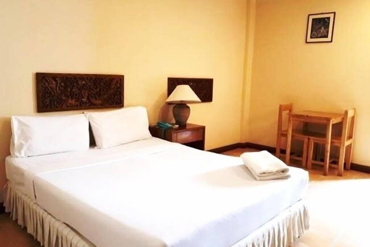 A hotel room with a bed, a nightstand, a lamp, a chair, and a framed picture on the wall.