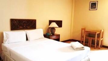A hotel room with a bed, a nightstand, a lamp, a chair, and a framed picture on the wall.