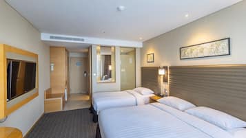 A hotel room with two beds, a TV, a desk, and a bathroom.