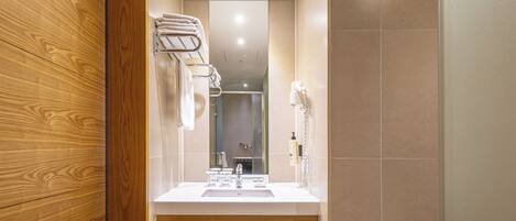Un baño moderno con tocador de madera, un espejo grande y un perchero para toallas.