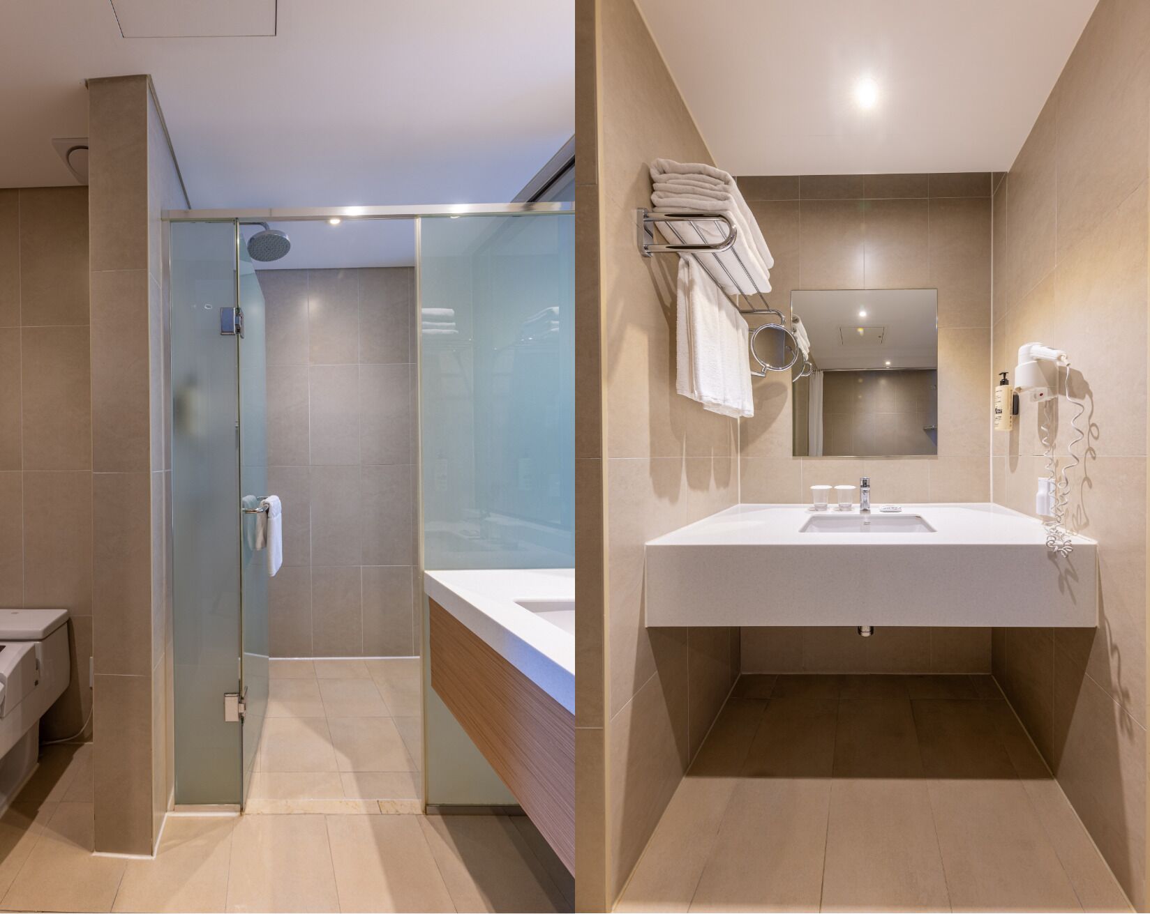 Un baño moderno con cabina de ducha de vidrio, un lavabo blanco con espejo y un toallero con toallas dobladas.