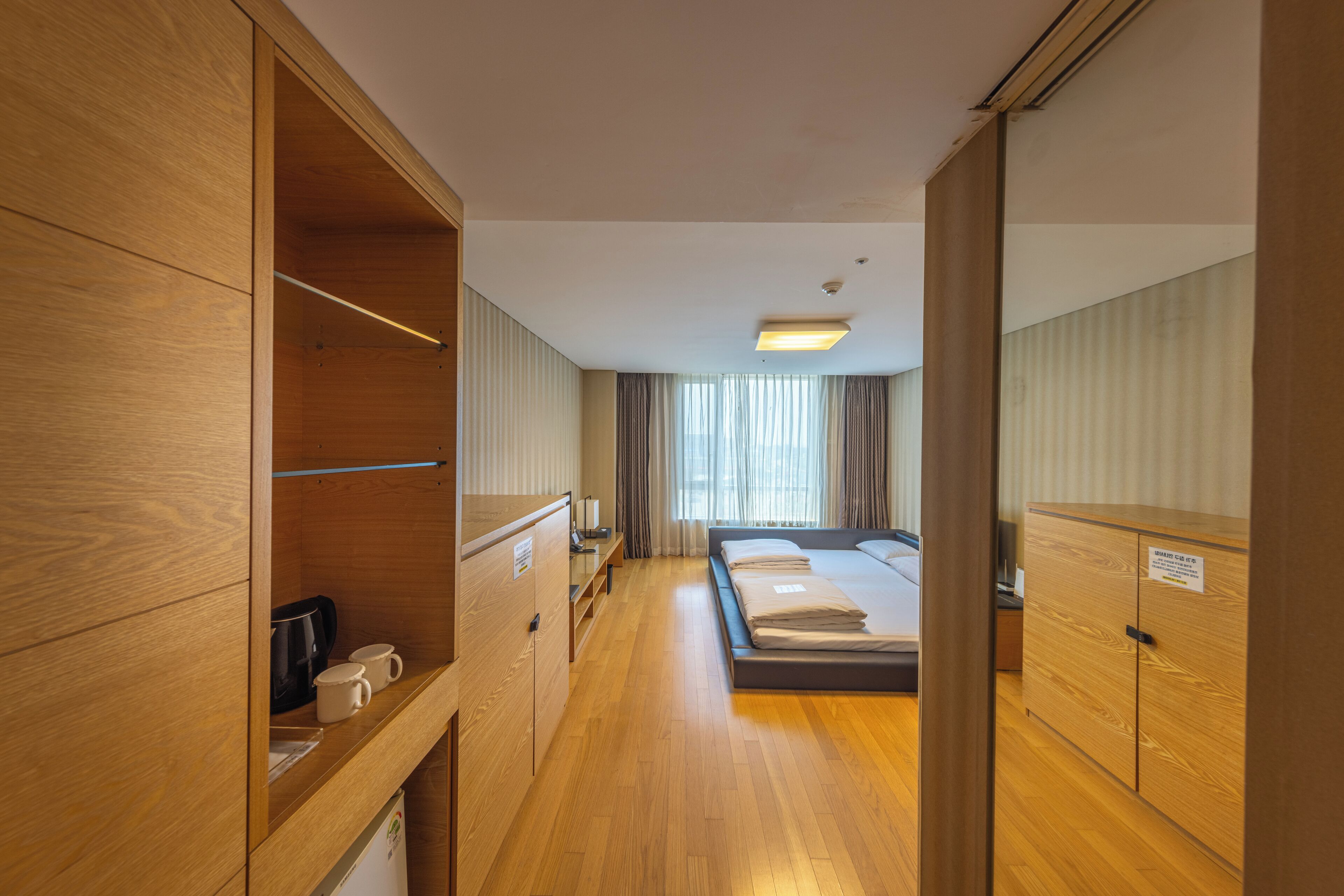 Una habitación de hotel con muebles de madera, una cama, un escritorio y un armario.