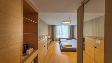 Una habitación de hotel con muebles de madera, una cama, un escritorio y un armario.