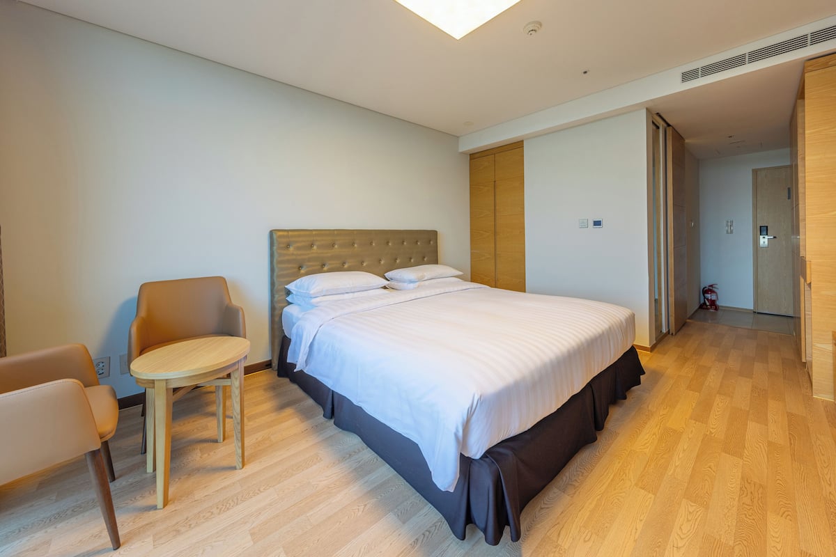 A modern hotel room with a large bed, a small round table, and a chair.