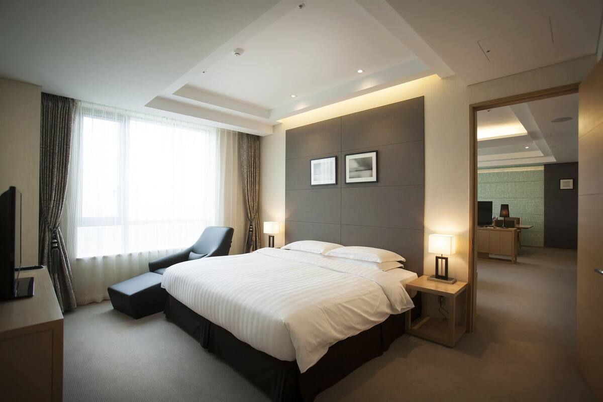 A modern hotel room with a large bed, bedside tables, a desk, and a television.