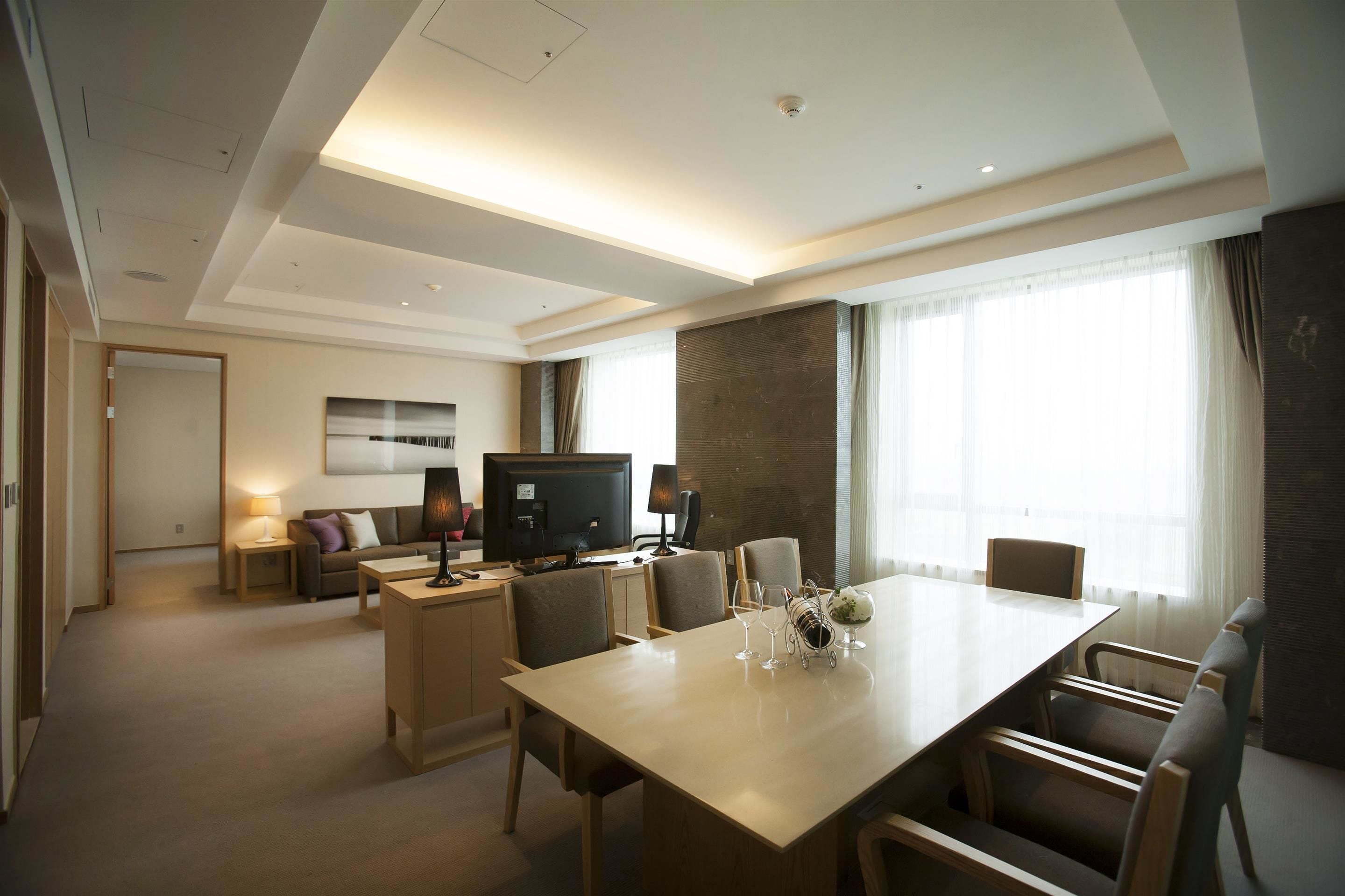 A hotel room with a dining area, a TV, and a sofa.