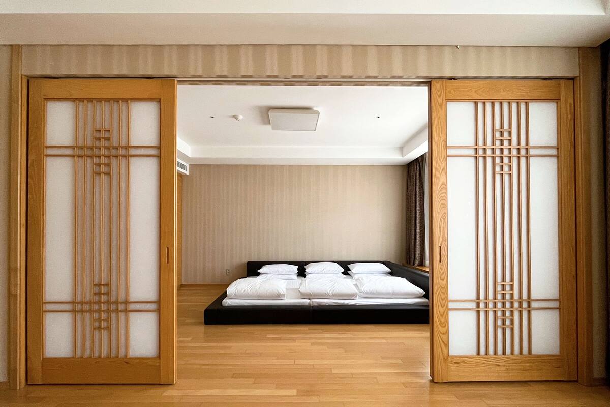A traditional Japanese-style room with a bed, sliding doors, and a wooden floor.
