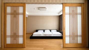 Una habitación japonesa tradicional con cama, puertas correderas y suelo de madera.