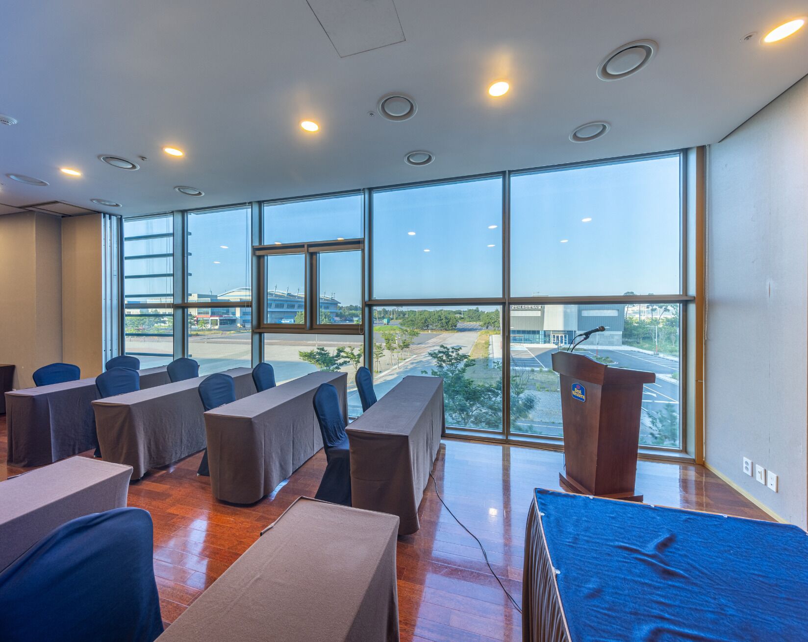 A conference room with a large window, a podium, and several tables with chairs.