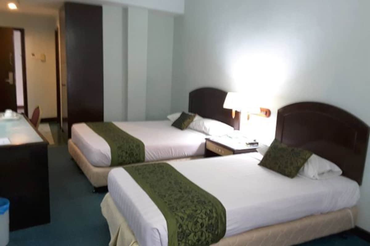 Une chambre d’hôtel avec deux lits, un bureau et une chaise.