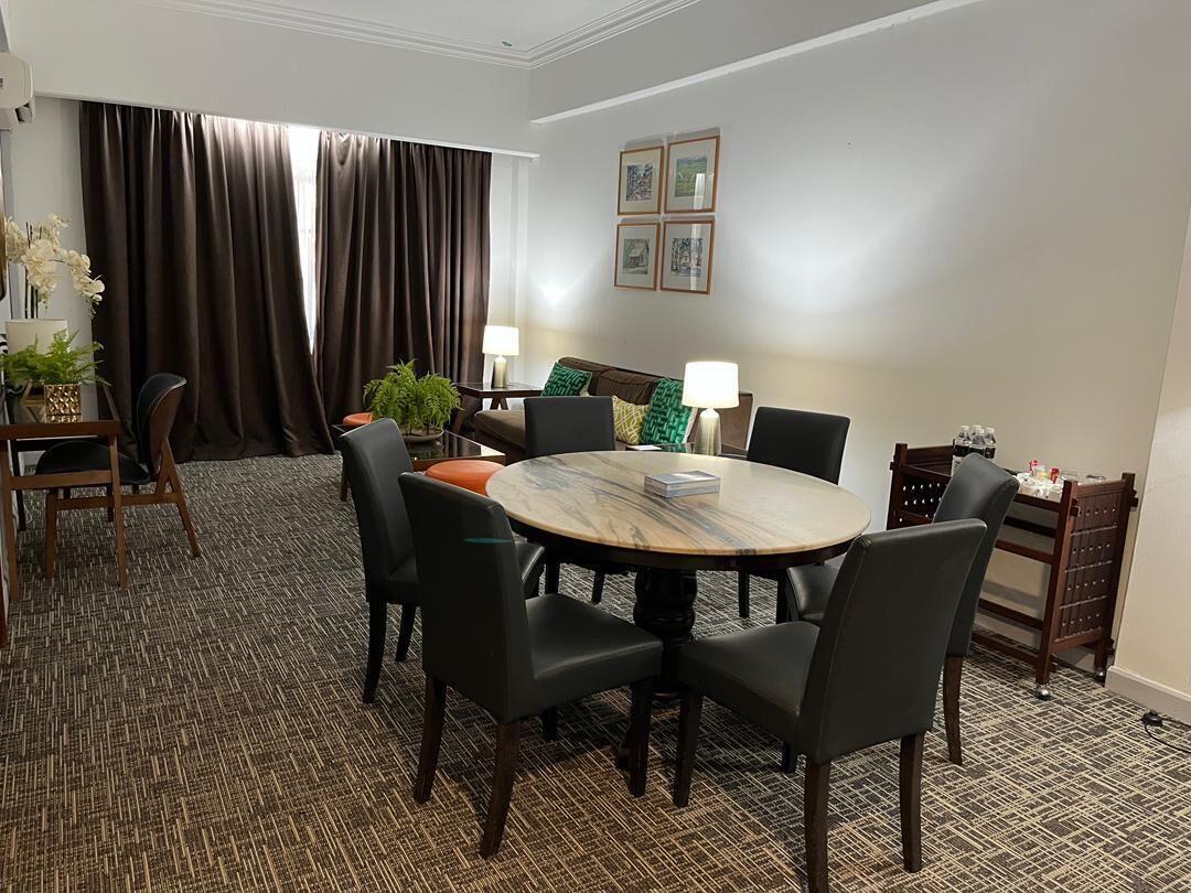 A conference room with a round table, chairs, a small side table, and a lamp.
