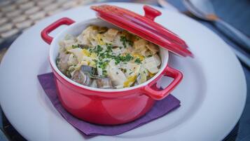 A red pot of food on a white plate with a purple napkin underneath.