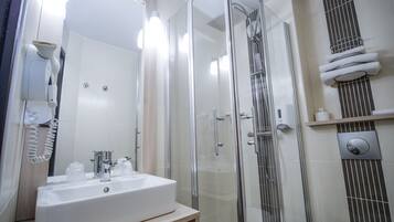 A modern bathroom with a glass-enclosed shower, a white sink, and a towel rack.