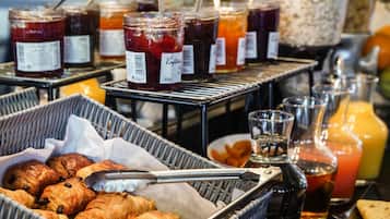 A breakfast buffet with pastries, jams, and juices.