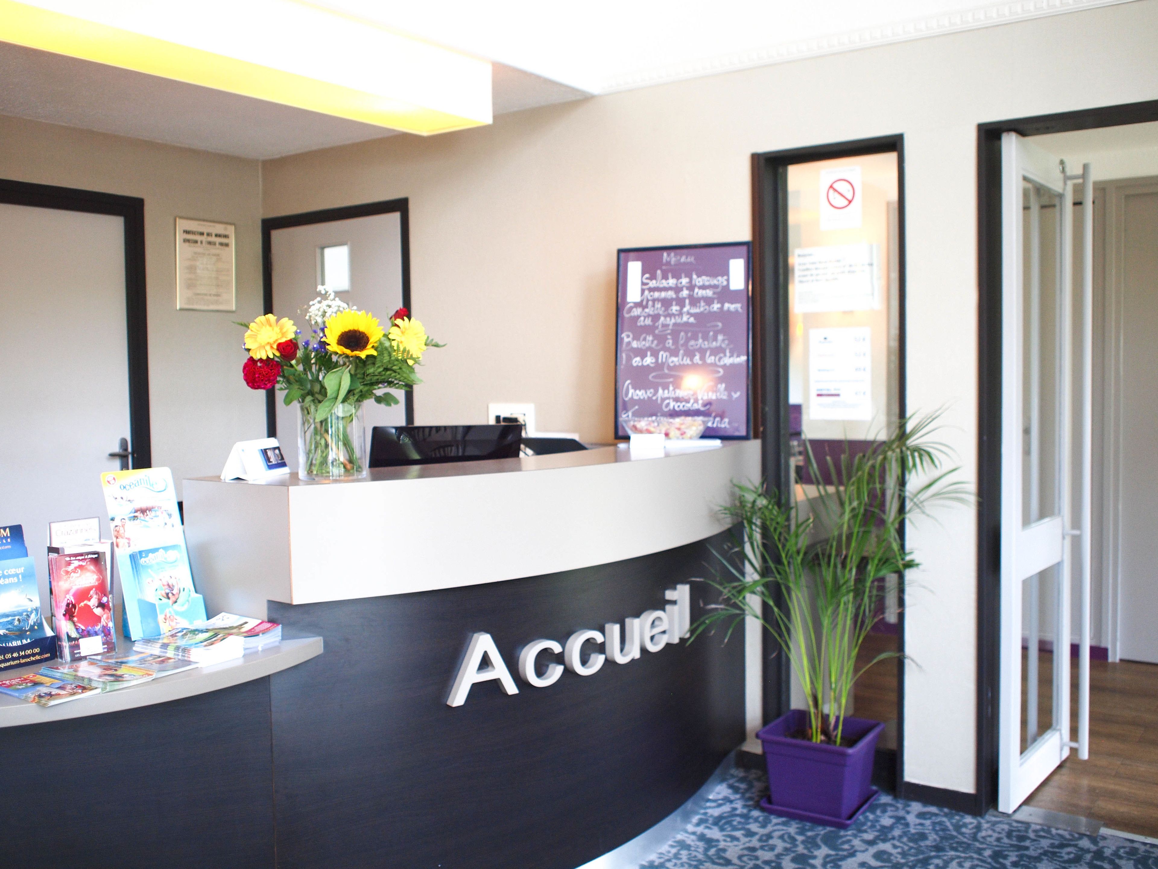 A reception desk with a sign reading "Accueil" and a menu board in the background.