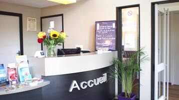 A reception desk with a sign reading "Accueil" and a menu board in the background.