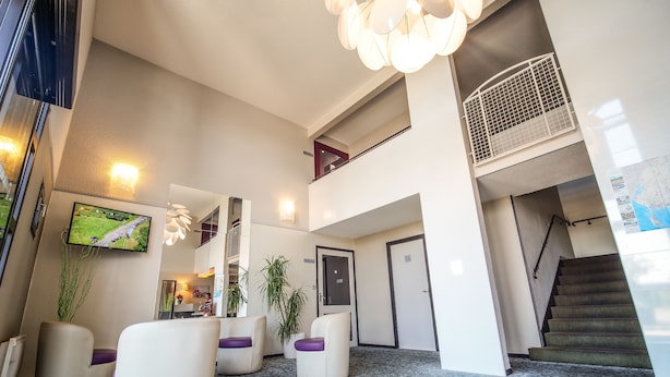 Een moderne lobby met een flatscreen televisie, comfortabele zitplaatsen, een trap en een decoratieve lamp.