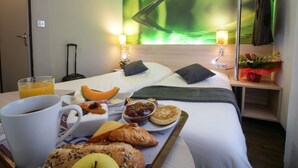 Een hotelkamer met een bed, een ontbijttafel en een muurschildering.