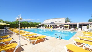 Una piscina al aire libre, sombrillas, sillones reclinables de piscina
