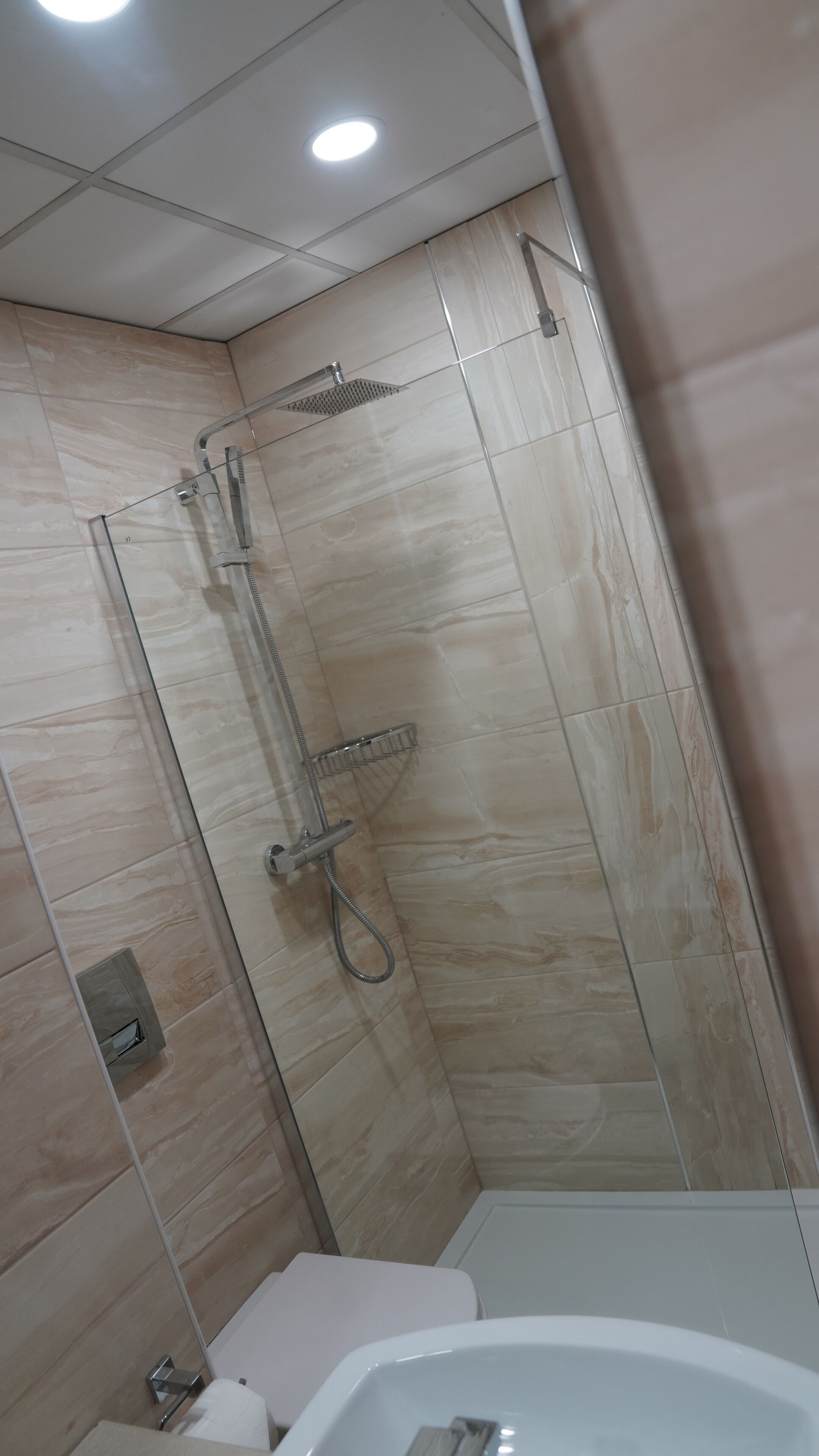 A modern bathroom with a glass-enclosed shower, a toilet, and a bathtub.