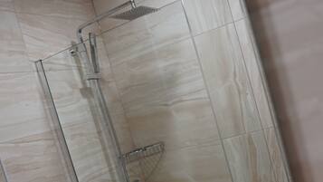 A modern bathroom with a glass-enclosed shower, a toilet, and a bathtub.